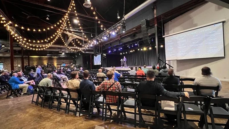 Vlad Iliushin as a speaker talking about mass exploitation and recon on the stage at BSides Nashville 2025