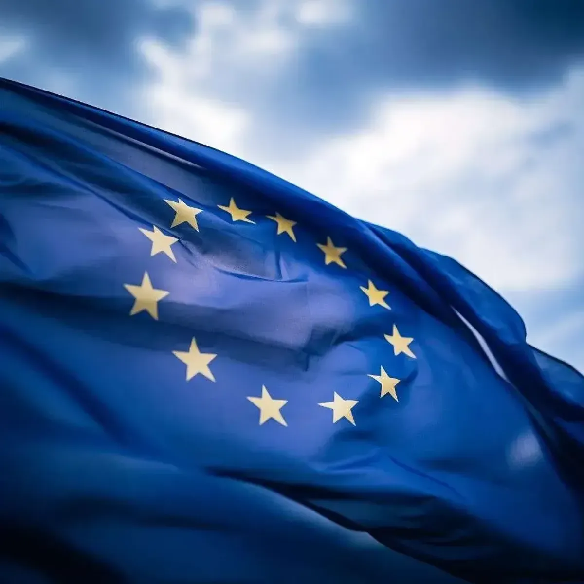 European Union flag waving against cloudy blue sky, symbolizing EU cybersecurity regulations and data protection compliance