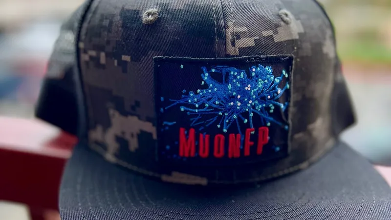 Gray camouflage baseball cap with rectangular patch displaying network fingerprints MUONFP.