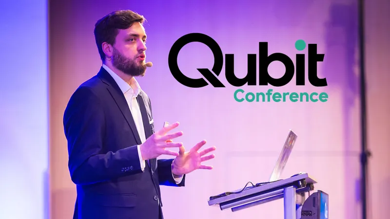 Vlad Iliushin from ELLIO as speaker presenting at Qubit Conference, wearing dark suit and gesturing while speaking from podium with purple stage lighting