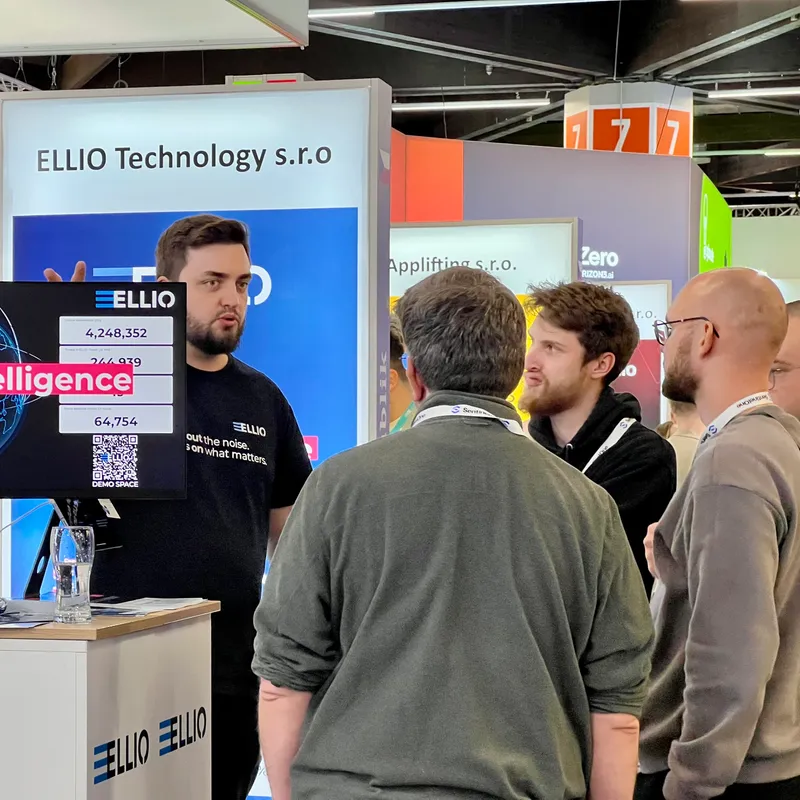 ELLIO Technology booth at trade show with representatives demonstrating cybersecurity solutions to visitors, featuring company branding and product displays